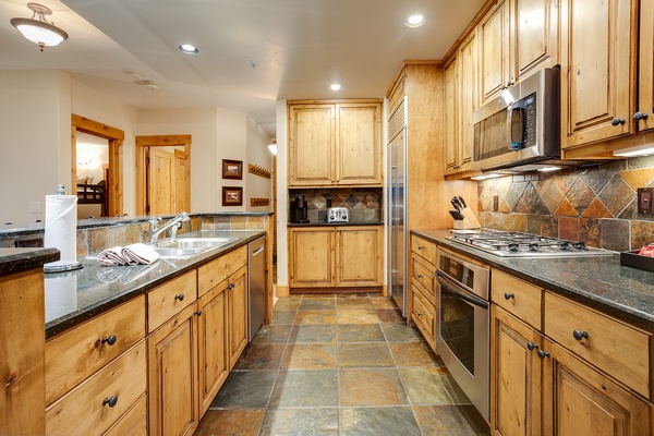 Your fully equipped kitchen with warm wood cabinetry, granite countertops, and stainless appliances invites you to cook meals just like home in a beautifully designed space.