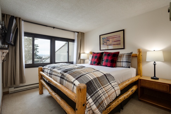 Wake up to stunning views through your bedroom window. Cozy plaid bedding and rustic log furniture create a welcoming mountain retreat where you'll rest deeply after your adventures.