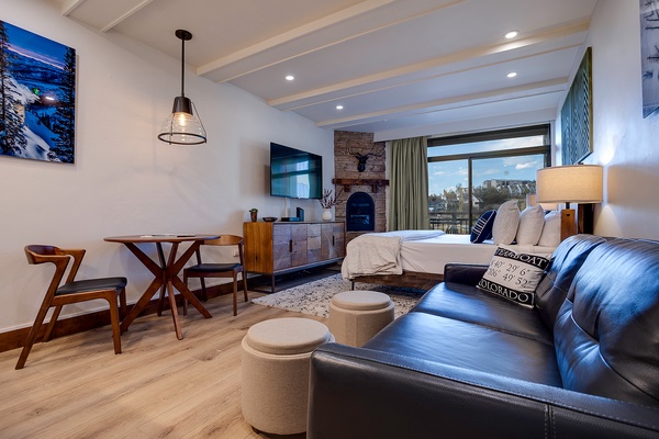 Unwind in your open-concept retreat with cozy fireplace, plush bedding, and a welcoming lounge area. Enjoy mountain views through expansive windows, a fully equipped dining nook, and modern comfort throughout your stay.