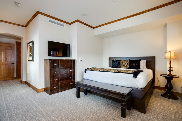 Sink into your plush bed after a day of adventure. Dark wood accents and warm lighting create a restful sanctuary where you'll unwind in comfort and style.