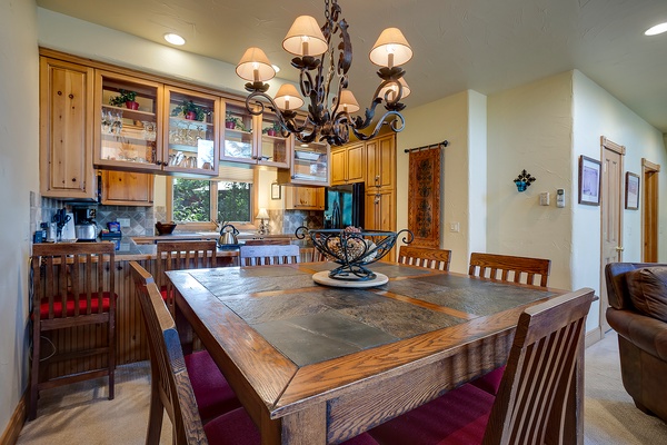 Gather around this handsome dining table under a stunning wrought-iron chandelier. The adjoining open kitchen invites you to whip up meals while staying connected with your group.