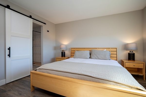 Sink into crisp white linens and warm wood tones in your serene bedroom. The charming barn door opens to your private ensuite, where every detail is designed for your comfort and relaxation.