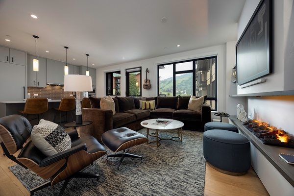 Sink into plush seating in your open-concept living space, where a warm fireplace and mountain vistas through expansive windows create the perfect backdrop for cozy evenings and memorable conversations.