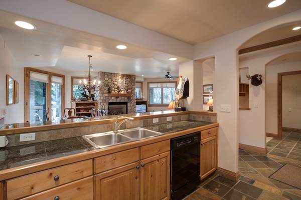 Cook up your favorite meals in this spacious kitchen with granite counters, a double sink, and dishwasher, all while enjoying the cozy stone fireplace and mountain views beyond.