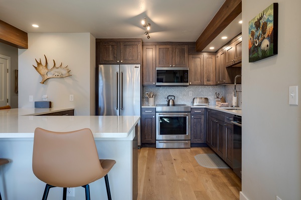 Your beautifully appointed kitchen features custom cabinetry, stainless appliances, and a sleek breakfast bar—perfect for whipping up morning coffee or evening meals.