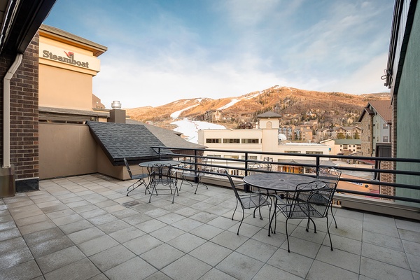 Rooftop terrace offers outdoor seating with mountain views, adjacent to a Steamboat-branded building in a ski resort setting.