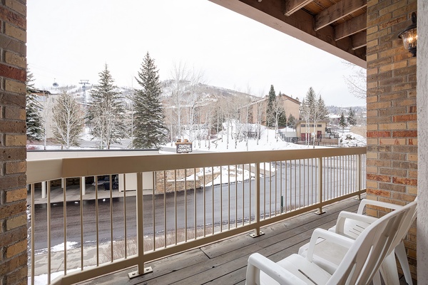 A snow-dusted ski village nestles among evergreens and mountain slopes, framed by a private balcony where winter adventure begins just steps away.