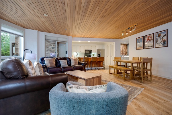 Relax beneath stunning wood ceilings in your spacious open-plan living area, where cozy seating, a full kitchen, and a welcoming dining table invite you to unwind after your adventures.