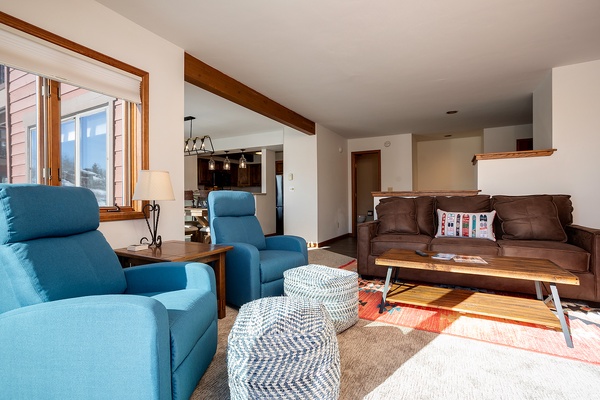 Sink into plush recliners and unwind in your bright, open-concept living space where warm wood beams and mountain light create the perfect retreat after a day of adventure.