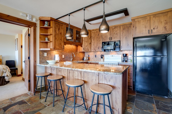 Your fully equipped kitchen features warm wood cabinetry, granite countertops, and a welcoming breakfast bar perfect for morning coffee or casual meals with loved ones.