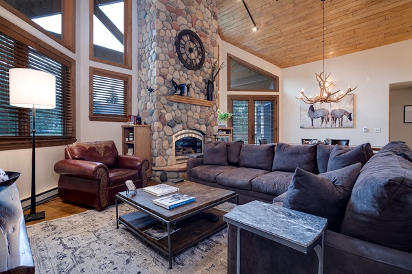 Sink into plush seating by your own stone fireplace, where rustic charm meets cozy mountain elegance under soaring wood ceilings.