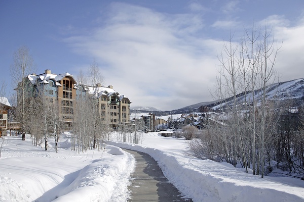 A pristine winter mountain village nestled among snow-covered peaks and aspens, offering scenic access to slopes and alpine charm.