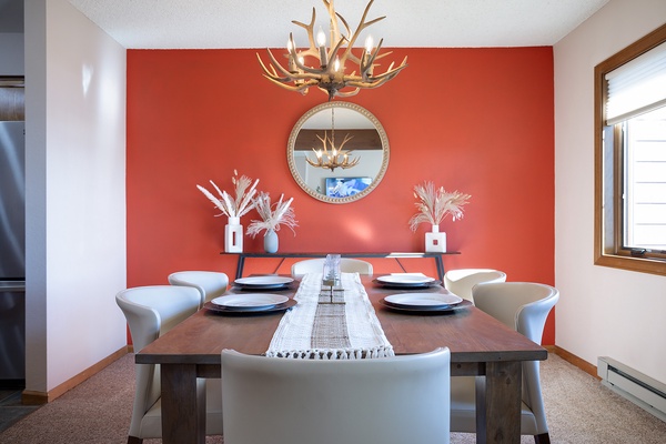 Gather around your private dining table beneath a striking antler chandelier, where vibrant coral tones and rustic elegance set the stage for memorable mountain meals together.