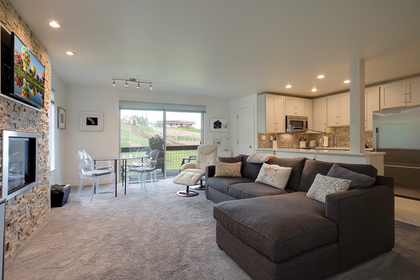 Unwind in your open-concept living space where a plush sectional invites movie nights by the fireplace, while your fully-equipped kitchen awaits your culinary adventures and vineyard views inspire relaxation.