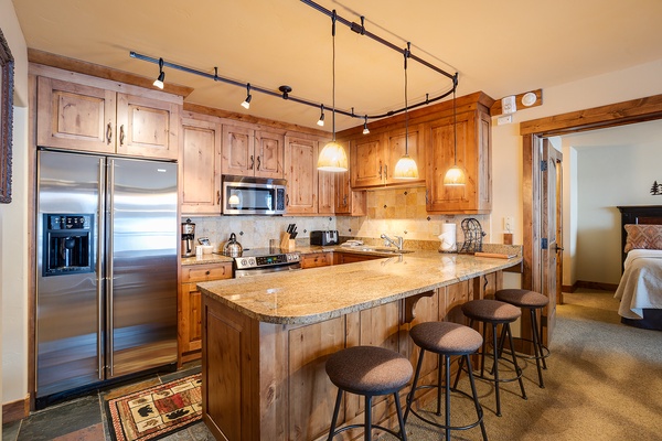 Gather around the spacious granite island with room for everyone. Warm wood cabinetry, stainless steel appliances, and pendant lighting create a welcoming space to cook, share meals, and make memories together.