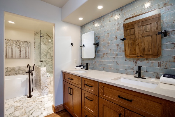 Unwind in your serene spa-like bathroom, featuring dual sinks, elegant tile work, and a luxurious soaking tub perfect for relaxing after a day exploring.