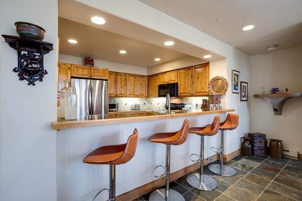 Your fully equipped kitchen features warm wood cabinetry, stainless steel appliances, and a welcoming breakfast bar with four seats—perfect for casual meals and morning coffee together.