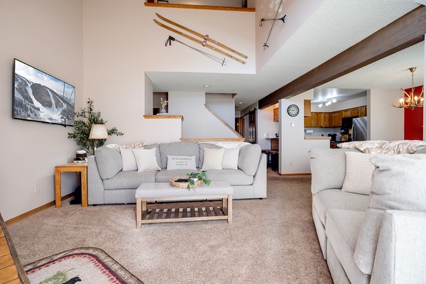 Sink into plush sofas and unwind in your spacious, light-filled living area with vaulted ceilings, rustic ski decor, and open sightlines to the kitchen—perfect for gathering after a day on the slopes.