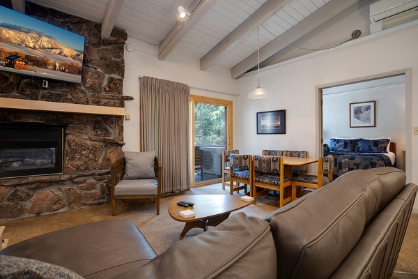 Unwind in your cozy mountain retreat with a crackling stone fireplace, plush seating, and vaulted ceilings that create an inviting, open atmosphere perfect for relaxation.