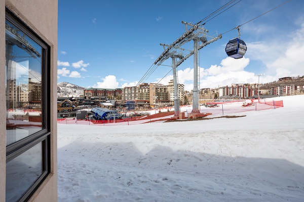 A ski resort base area with gondola access, surrounded by mountain residences and snowy slopes, offering convenient proximity to winter activities.