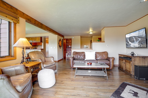 Unwind in your spacious living room with cozy leather seating, rustic wood beams, and a flat-screen TV perfect for mountain movie nights after a day of adventure.