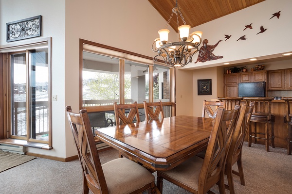 Gather around the handcrafted dining table under vaulted wood ceilings, where warm light and whimsical bird art create an inviting space for shared meals and memorable conversations.