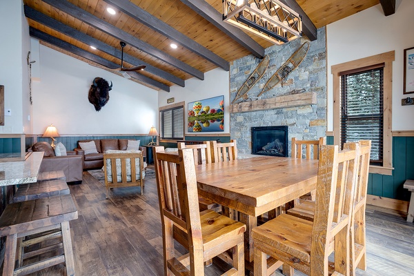 Gather around the handcrafted dining table where rustic wood beams meet modern mountain elegance. The soaring stone fireplace and cozy seating invite you to unwind after your adventures.