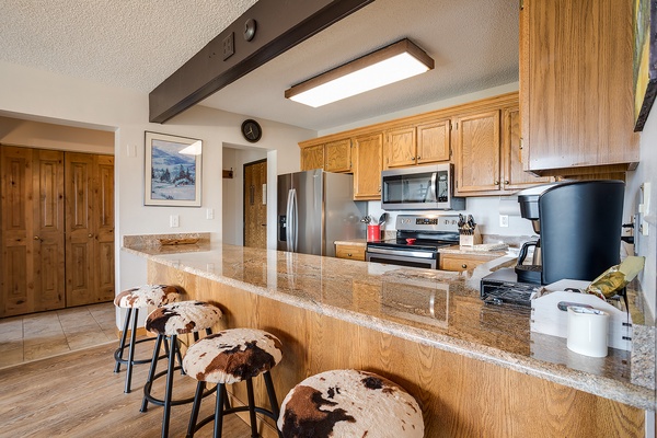 Your fully-equipped kitchen features granite countertops, stainless-steel appliances, and a breakfast bar with cowhide stools, perfect for morning coffee or casual meals.
