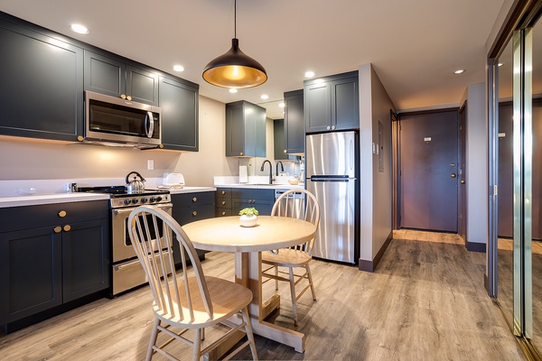 Your fully equipped kitchen features elegant dark cabinetry, stainless steel appliances, and a cozy dining nook—perfect for preparing and enjoying homemade meals during your stay.