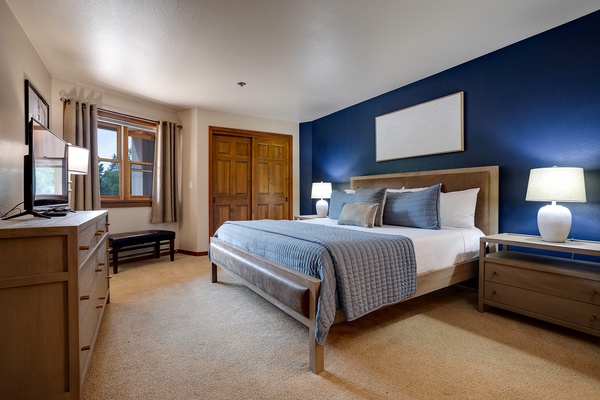 Sink into this inviting bedroom with crisp linens and a calming deep blue accent wall, your perfect retreat after a day of adventure. Soft lighting and cozy textures create a peaceful space to relax and recharge.