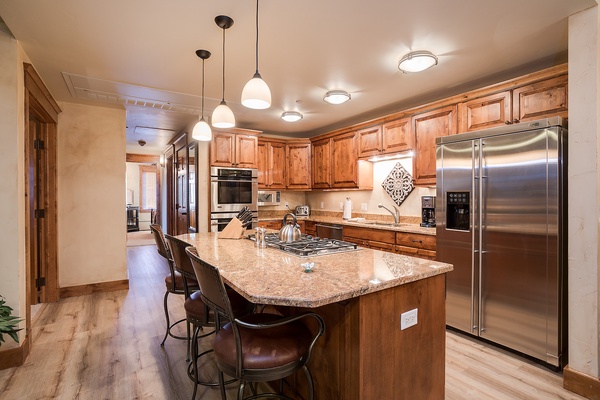 Gather around this spacious gourmet kitchen where rich wood cabinetry, granite countertops, and stainless steel appliances await your culinary adventures. The center island seats four, perfect for cooking together or enjoying morning coffee.