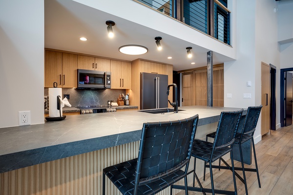 Gather at your spacious kitchen island, where modern design meets warm wood tones. Prep meals with sleek appliances and dine together with seating for everyone under bright, welcoming light.