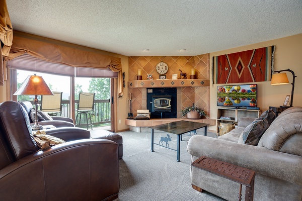Unwind in your cozy living room, where plush seating and a warm fireplace invite you to relax after a day of adventure, with natural light and patio access.