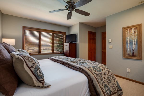 Unwind in your serene bedroom, where soft linens and gentle ceiling fan breezes promise restful nights. Natural light filters through wooden blinds, creating a peaceful retreat after your adventures.