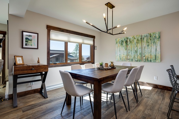 Gather around this inviting dining table where shared meals become treasured memories. The modern chandelier and natural light create a warm ambiance perfect for your morning coffee or evening dinners.