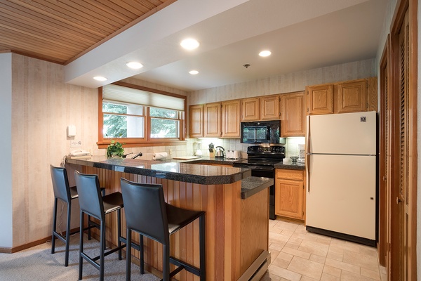 Your fully equipped kitchen features warm wood cabinetry, granite countertops, and modern appliances. Gather at the breakfast bar for morning coffee or casual meals together.