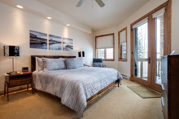 Wake to natural light streaming through your private balcony doors in this serene bedroom, where plush bedding and mountain-modern décor invite you to unwind completely after a day exploring.