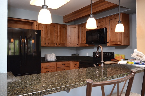 Your fully equipped kitchen features rich wood cabinetry, granite countertops, and modern appliances—perfect for preparing meals together while enjoying the open, inviting layout.