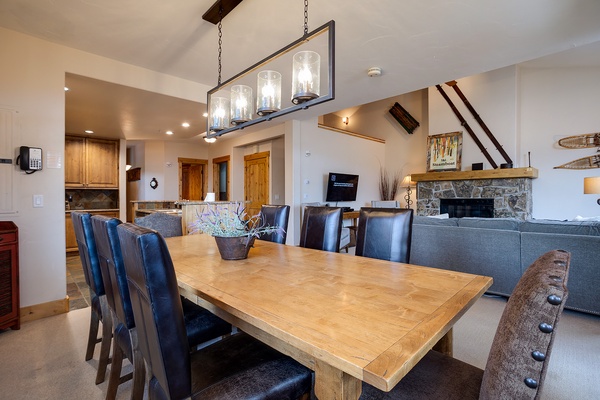 Gather around this spacious dining table where you'll enjoy meals together under warm lighting. The open layout connects to your cozy stone fireplace and well-equipped kitchen, perfect for memorable evenings.