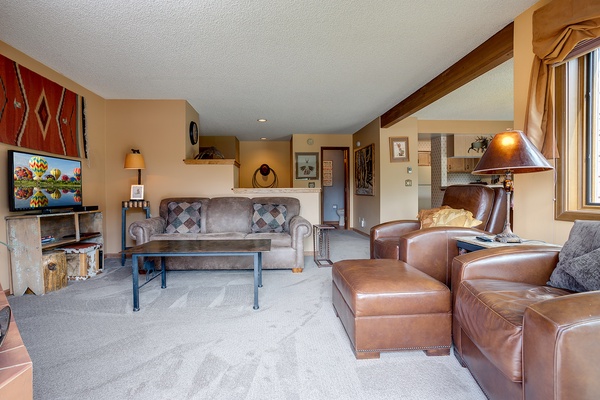 Sink into plush leather seating and unwind in your spacious living room, where warm wood accents and thoughtful decor create a cozy mountain retreat after a day of adventure.