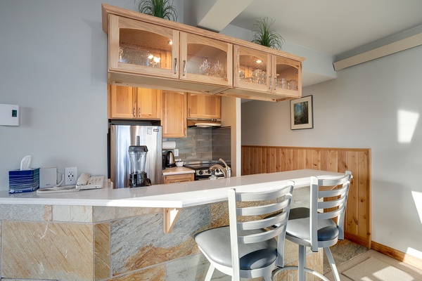 Your fully equipped kitchen features warm wood cabinetry, stainless appliances, and a convenient breakfast bar—perfect for enjoying morning coffee or preparing memorable meals together.