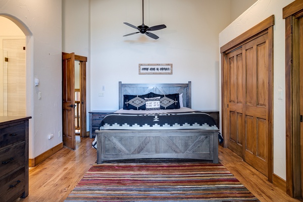 Sink into the plush bedding beneath soaring ceilings and a gentle ceiling fan. Rich wooden accents, a cozy striped rug, and thoughtful details create your perfect retreat after a day of exploring.