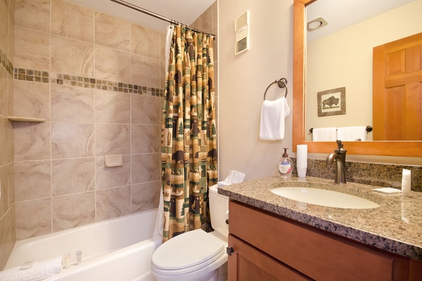 Refresh in your private bathroom with a sleek granite vanity, soaking tub with tile surround, and thoughtful touches like fresh towels and rustic wildlife accents that add a cozy charm.