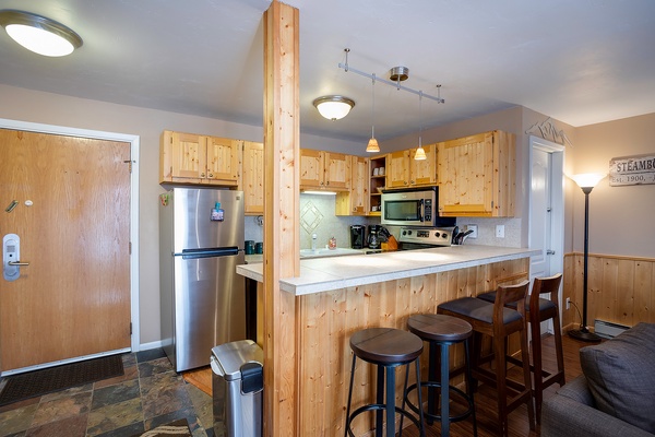 Gather around the welcoming kitchen island with seating for four, where stainless steel appliances and warm wood cabinetry create a relaxed mountain retreat vibe for your culinary adventures.