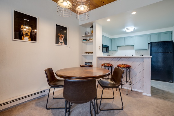 Gather at your own stylish dining table beneath warm pendant lights, with a fully-equipped kitchen featuring soft blue cabinetry just steps away.