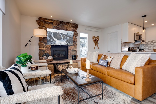 Unwind in your cozy living room featuring a stunning stone fireplace, plush leather seating, and mountain-modern décor. The open layout connects seamlessly to your fully-equipped kitchen for easy entertaining.