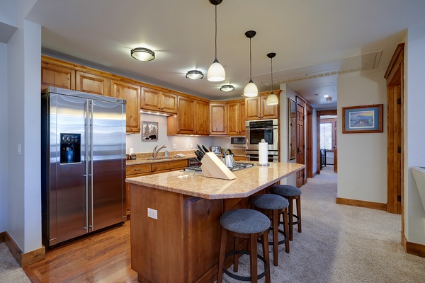 A beautifully appointed kitchen awaits your culinary adventures, featuring granite countertops, stainless steel appliances, and an island with seating for casual meals or morning coffee.