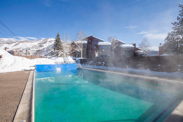Outdoor heated pool set against a stunning winter mountain backdrop, perfect for soaking after a day on the slopes.