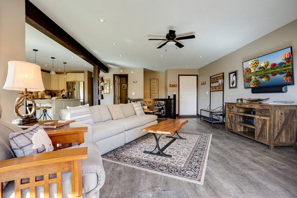 Sink into plush seating in this stylish open-concept living space, where rustic wood accents meet modern comfort—your perfect home base for relaxation and entertainment.
