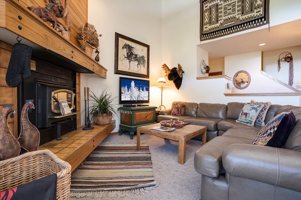Sink into the soft leather sectional by the glowing fireplace, where rustic wood beams and mountain-inspired art welcome you to your cozy retreat.